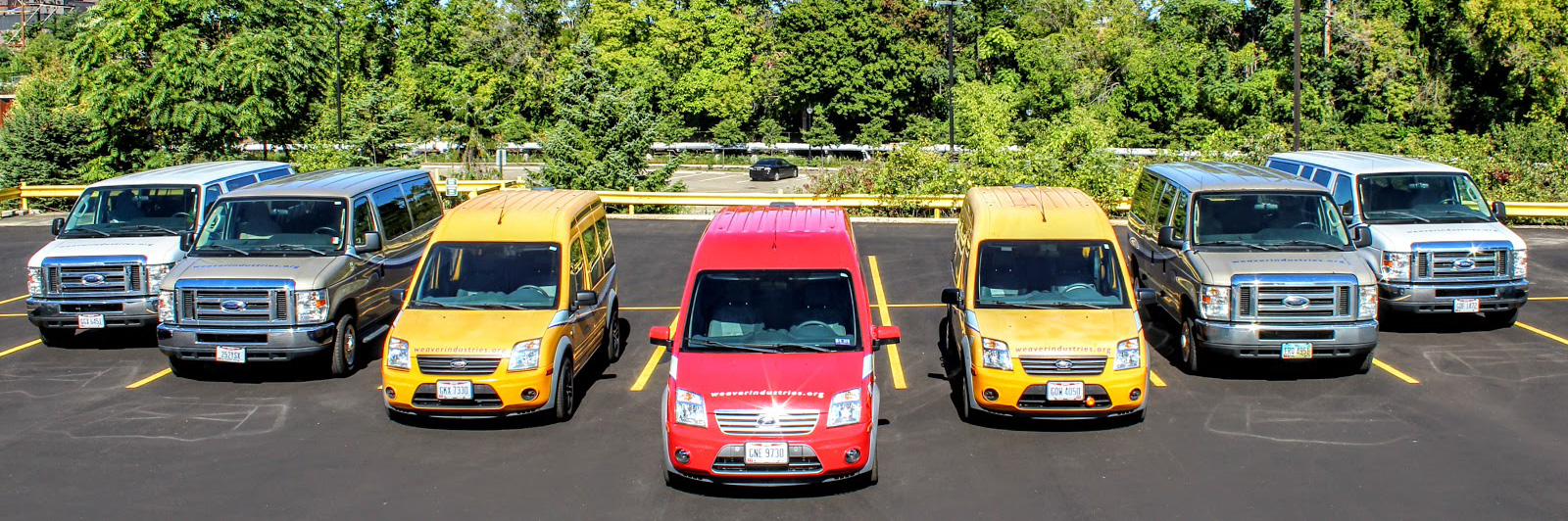 Fleet of seven Weaver commercial vans parked in a row, featuring white, beige, yellow, and red vehicles.